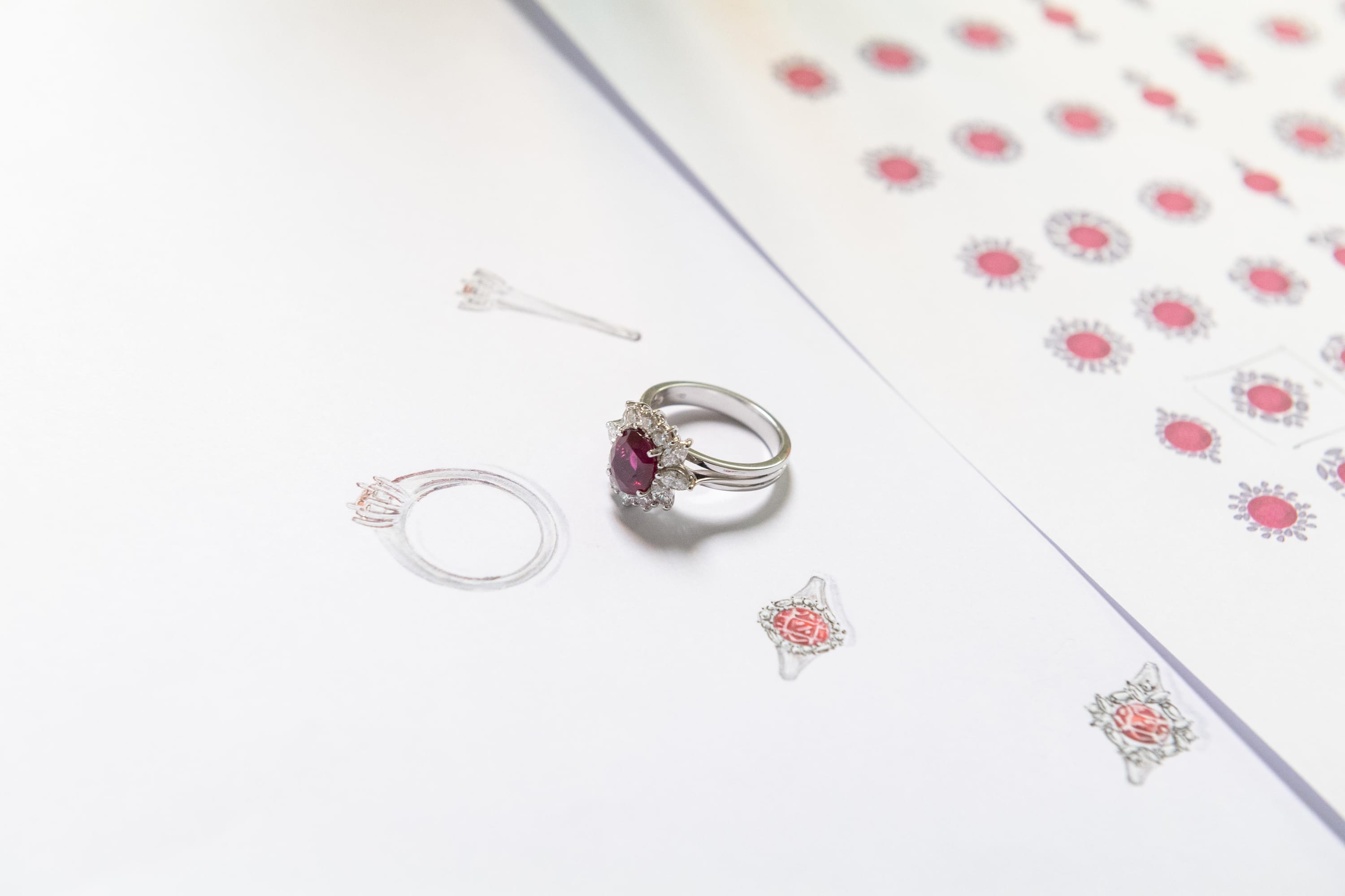 Anello con rubino e diamanti appoggiato sui disegni di progetto da cui è nato